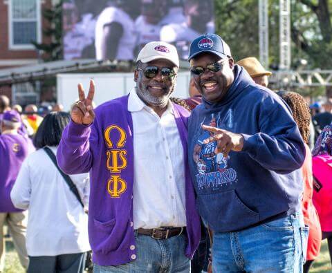 Two fraternity alumni greeting each other during homecoming concert